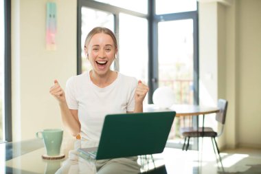 Dizüstü bilgisayarı olan beyaz, güzel bir kadın şok olmuş, heyecanlı ve mutlu, gülüyor ve başarıyı kutluyor.!