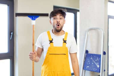 Genç ve yakışıklı bir adam şok olmuş ve şaşırmış hissediyor. pencere temizleme konsepti