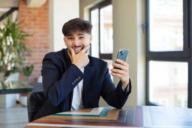 Ağzı ve gözleri açık ve eli çenesinde genç yakışıklı bir adam. akıllı telefon kavramı