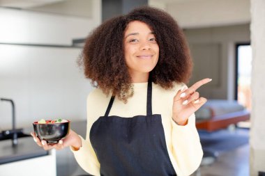 Güzel afro siyah kadın neşeyle gülümsüyor, mutlu hissediyor ve bir tarafı işaret ediyor. Japon eriştesi kavramı.