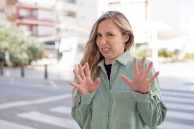 Güzel bir kadın tiksinmiş ve rahatsız olmuş hissediyor, dilini dışarı çıkarıyor, iğrenç ve iğrenç bir şeyden hoşlanmıyor.