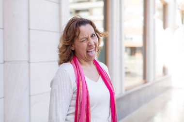 Orta yaşlı, neşeli, kaygısız, asi tavırlı, şakacı ve dilsiz bir kadın, eğleniyor.