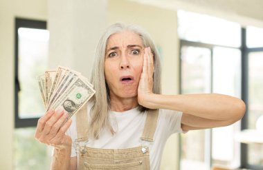 Güzel bir son sınıf öğrencisi son derece şaşırmış ve şaşırmış hissediyor. Dolar banknotlarıyla