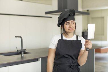 Genç bir kadın gülümsüyor ve mutlu ve kendinden emin bir ifadeyle bakıyor. Şef konsepti