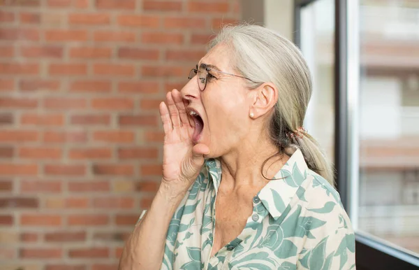 stock image senior pretty woman profile view, looking happy and excited, shouting and calling to copy space on the side