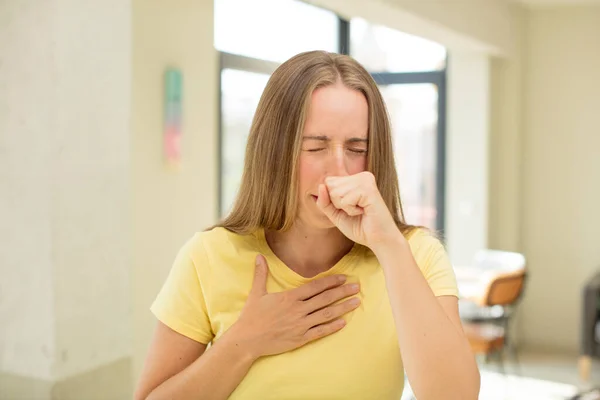 喉の痛みやインフルエンザの症状でかなりブロンドの女性が口を覆い咳をして — ストック写真