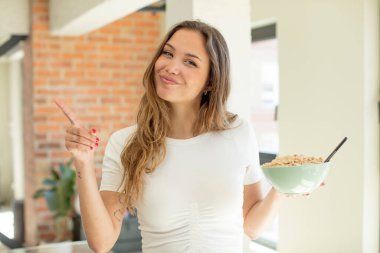 Güzel bir kadın neşeyle gülümsüyor, mutlu hissediyor ve bir tarafı işaret ediyor. Kahvaltı kasesi konsepti