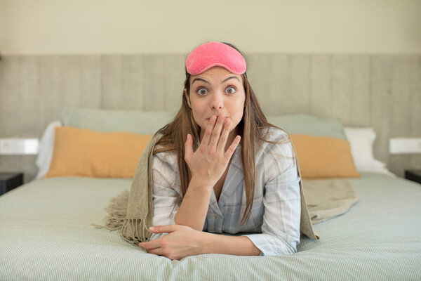 young pretty woman covering mouth with a hand and shocked or surprised expression. nightwear concept