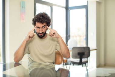 Masasında fotokopi yeri olan genç sakallı adam.