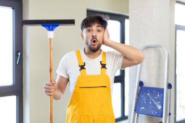 Genç ve yakışıklı bir adam şok olmuş ve şaşırmış hissediyor. pencere temizleme konsepti