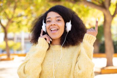 Güzel afro siyah kadın bir fikri fark ettikten sonra mutlu ve heyecanlı bir dahi gibi hissediyor. kulaklıkla müzik dinlemek