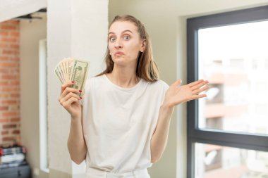 Omuz silkmek, kafası karışık ve kararsız hissetmek. Dolar banknotları konsepti