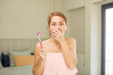 Genç ve güzel bir kadın ağzını eliyle kapatıyor ve şok olmuş ya da şaşırmış bir ifade takınıyor. gargara konsepti