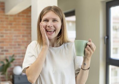 Genç ve güzel bir kadın inanılmaz bir şey karşısında kendini mutlu ve şaşkın hissediyor. Kahve fincanı konsepti
