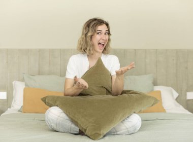 Güzel bir kadın mutlu bir şekilde gülümser ve bir konsept sunar ya da gösterir. Gece elbisesi ve yatak odası konsepti