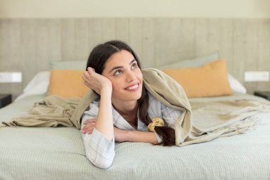 Mutlu, kendinden emin ve elleri çenesinde gülümseyen genç bir manken. dinlenme ve gecelik konsepti