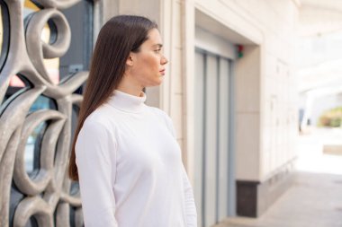 pretty young adult woman on profile view looking to copy space ahead, thinking, imagining or daydreaming