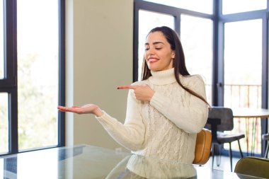 pretty caucasian woman smiling, feeling happy, carefree and satisfied, pointing to concept or idea on copy space on the side