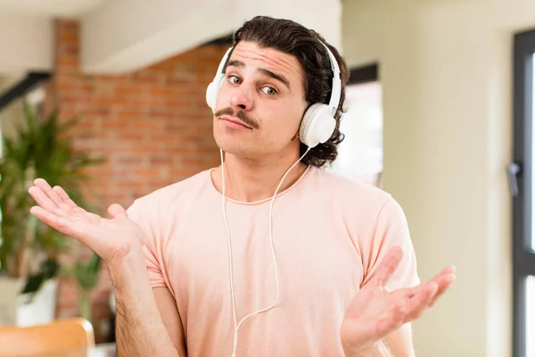 若いハンサムな男は家のインテリアでヘッドフォンで音楽を聞いて — ストック写真