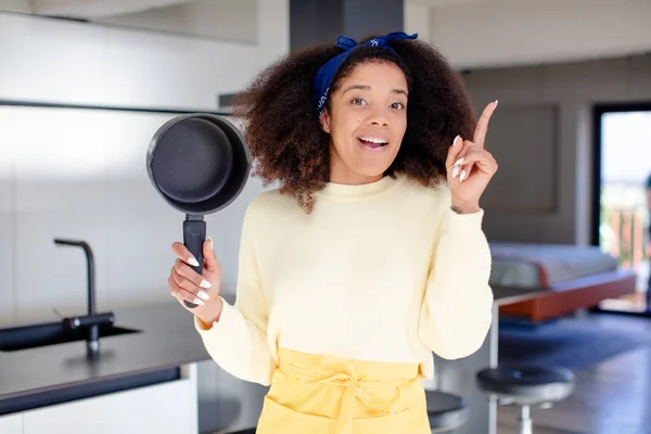 stock image pretty afro black woman feeling like a happy and excited genius after realizing an idea. home chef concept