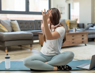 Elleri havada yoga yapan genç bir kadın. Öfkeli, sinirli, stresli ve üzgün.