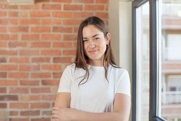 stock image young adult pretty woman smiling to camera with crossed arms and a happy, confident, satisfied expression, lateral view