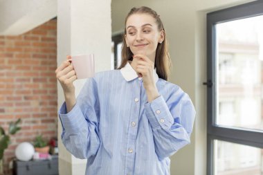 Mutlu ve kendinden emin bir ifadeyle gülümsüyor. Evde kahve fincanı var. kahve fincanı evde.