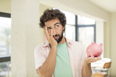 Çılgın sakallı adam bıkkın, yorgun ve uykulu hissediyor. Domuz kumbarası konsepti