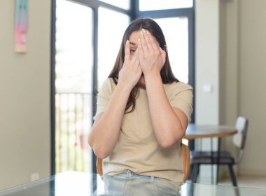 Genç, güzel bir kadın kendini stresli, endişeli, endişeli ya da korkmuş hissediyor. Elleri başının üstünde, hatayla panikliyor.