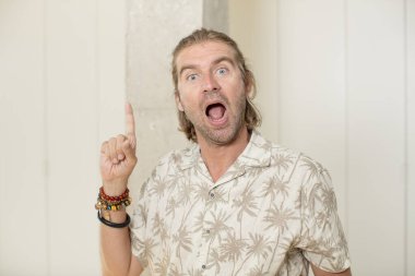 Genç sarışın yetişkin bir adam bir fikri fark ettikten sonra mutlu ve heyecanlı bir dahi gibi hissediyor, neşeli bir şekilde parmağını kaldırıyor, eureka!