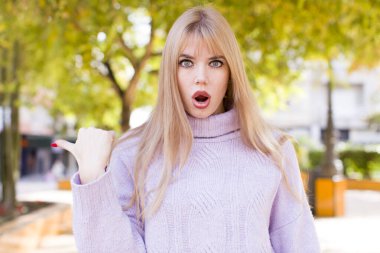 Genç ve güzel bir kadın inançsızlıktan şaşkın şaşkın bakıyor, yan taraftaki objeyi işaret ediyor ve diyor ki: