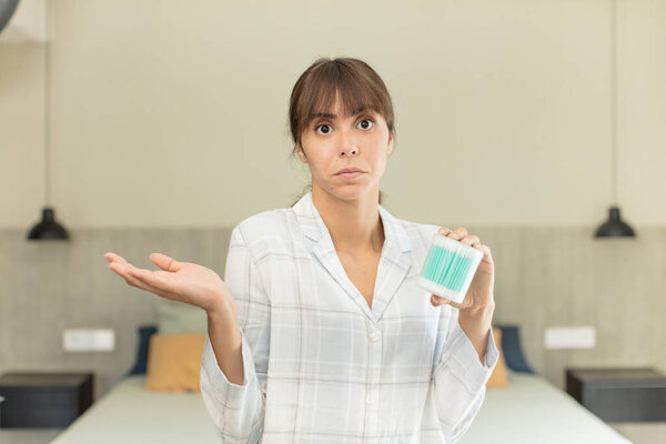 young pretty woman shrugging, feeling confused and uncertain ear bud concept