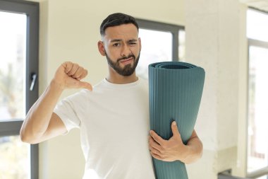 Arap yakışıklı adam, Arap adam kendini kötü hissediyor, baş parmağını kaldırıyor. yoga mat konsepti