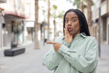 Afro güzel siyahi kadın şok olmuş bir ifadeyle şaşırmış hisseder ve yüzünü gösterir.