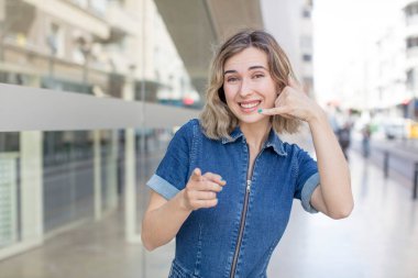 Güzel bir kadın neşeyle gülümsüyor ve kamerayı işaret ediyor. Sonra seni arıyor, telefonla konuşuyor.