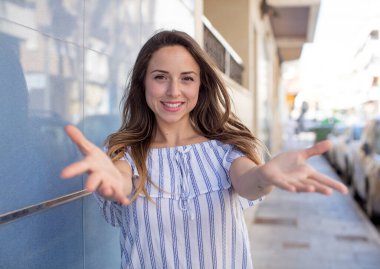 Güzel bir kadın neşeyle gülümsüyor sıcak, dostça, sevgi dolu bir kucak veriyor, mutlu ve sevimli hissediyor.