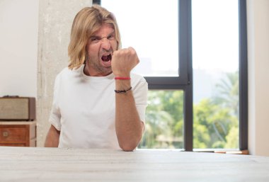 Masasında fotokopi yeri olan genç sarışın yetişkin bir adam.