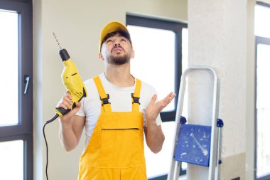 Genç yakışıklı adam ellerini havaya kaldırarak çığlık atıyor. Tamirci ve matkap konsepti