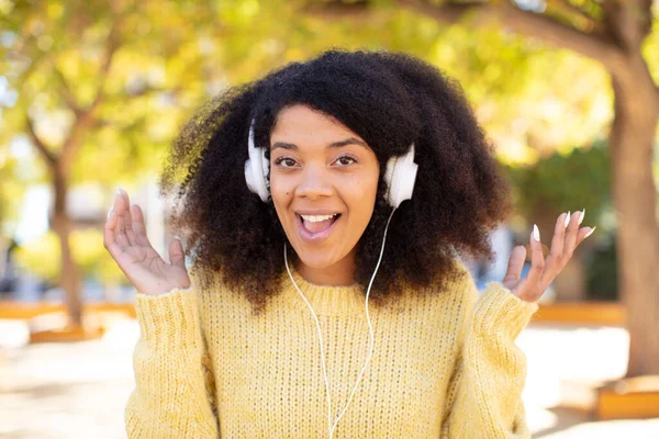 pretty afro black woman feeling happy and astonished at something unbelievable. listening music with headphones