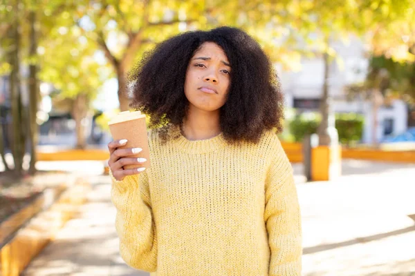 pretty afro black woman feeling sad and whiney with an unhappy look and crying. take away coffee concept