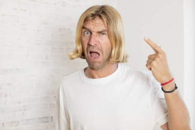 Genç sarışın yetişkin bir adam kafası karışık ve şaşkın hissediyor. Deli, deli ya da aklını kaçırmış olduğunu gösteriyor.