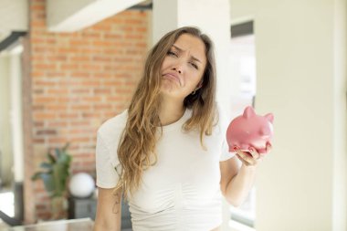 Güzel bir kadın üzgün ve mızmızlanıyor. Mutsuz bir bakışı var ve ağlıyor. Domuz kumbarası konsepti