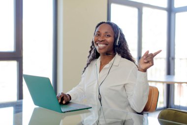 Siyah afro kadın neşeyle gülümsüyor, mutlu hissediyor ve bir tarafı işaret ediyor. tele pazarlamacı kavramı
