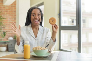 Siyah afro kadın kendini mutlu hissediyor ve inanılmaz bir şeye hayret ediyor. kahvaltı kavramı