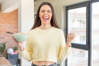 Oldukça genç bir model kızgın, sinirli ve sinirli görünüyor. Kahvaltı kasesi konsepti