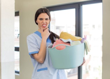 Ağzı ve gözleri açık ve elleri çenesinde güzel genç bir manken. Temizlikçi ve çamaşır konsepti