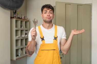 Genç yakışıklı adam omuz silkiyor, kafası karışık ve kararsız. Becerikli adam kavramı