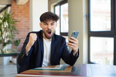 Genç ve yakışıklı bir adam sinirli, sinirli ve sinirli görünüyor. akıllı telefon kavramı