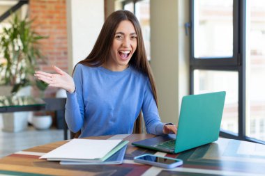 İnanılmaz bir şey karşısında mutlu ve şaşkın hissediyorum. dizüstü bilgisayar ve masa konsepti