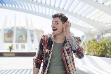 Yakışıklı adam mutlu görünüyor, dinliyor, gizli bir konuşma veya dedikodu duymaya çalışıyor, kulak misafiri oluyor.